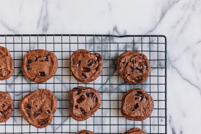 Chocolate chip cookies on a metal cooling rack on top of a marble countertop